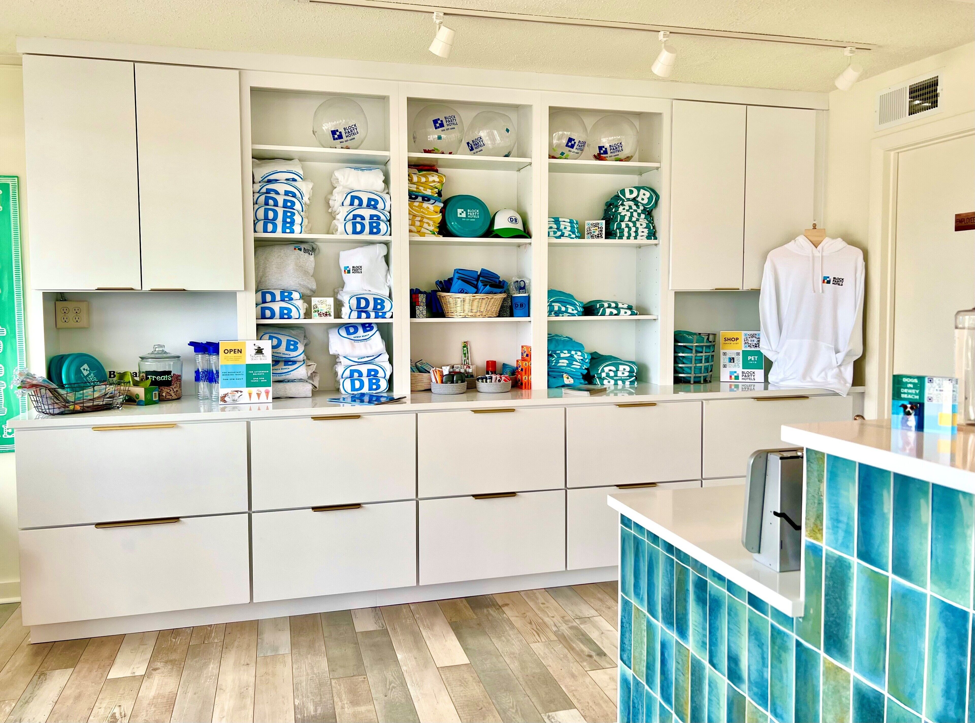 A kitchen with white cabinets, a countertop with various items, and a blue tiled backsplash.
