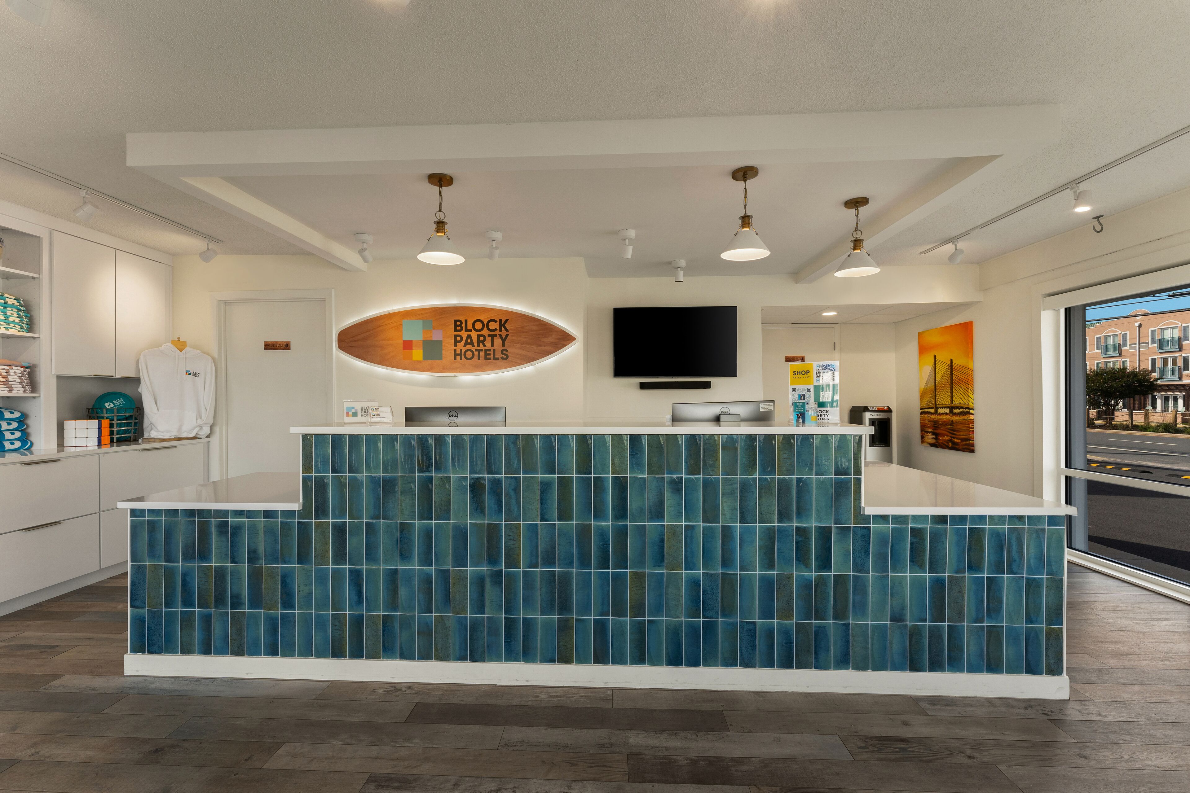 Un área de recepción con mostrador de azulejos azules, un televisor de pantalla plana y un cartel de Block Party Hotels.