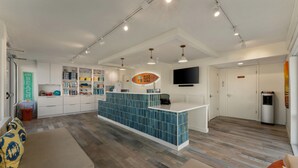 A hotel lobby with a reception desk, a sofa, and a television mounted on the wall. - Atlantic Oceanside Dewey (Dewey Beach)