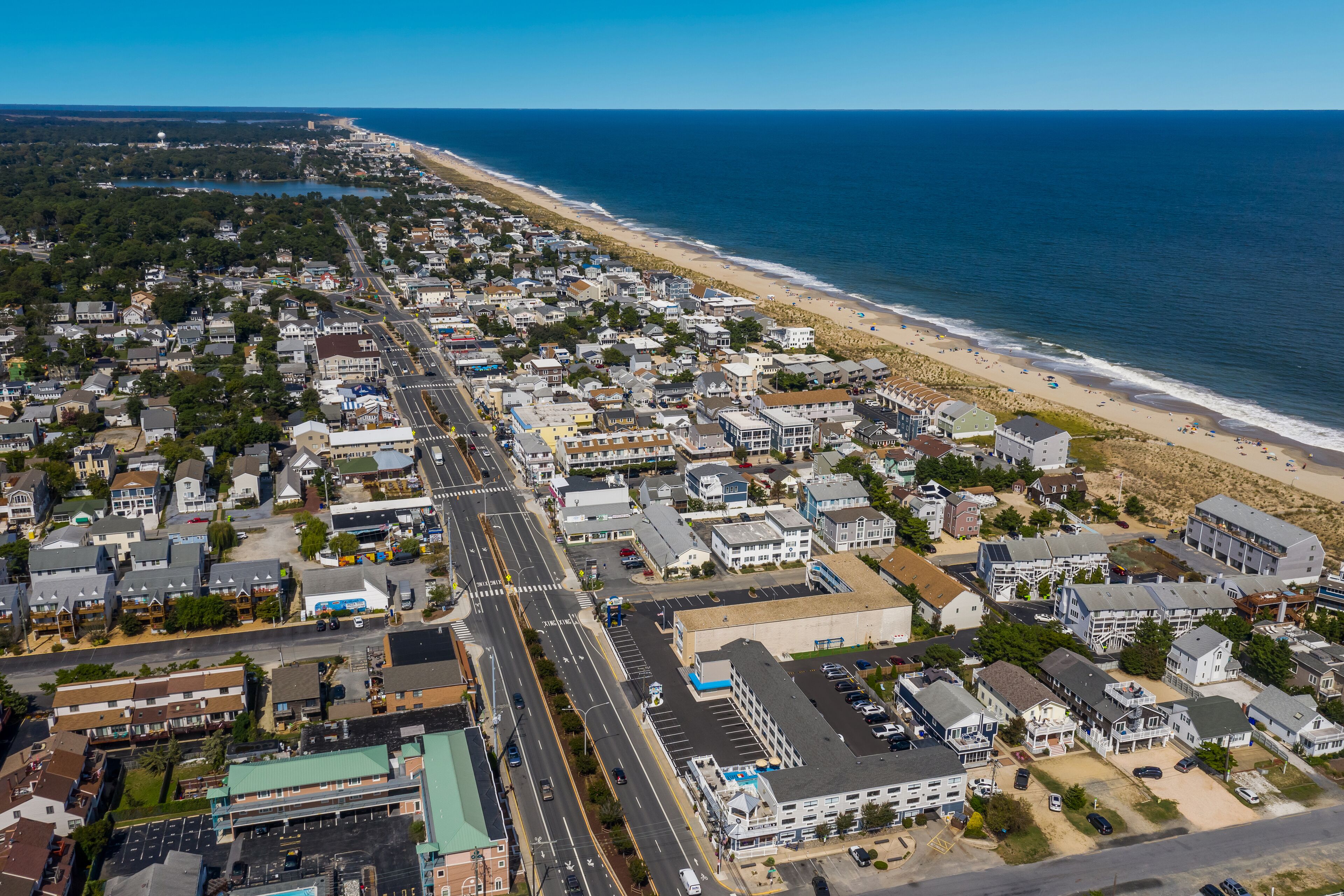 An aerial view of a coastal town with a beach, roads, and buildings.