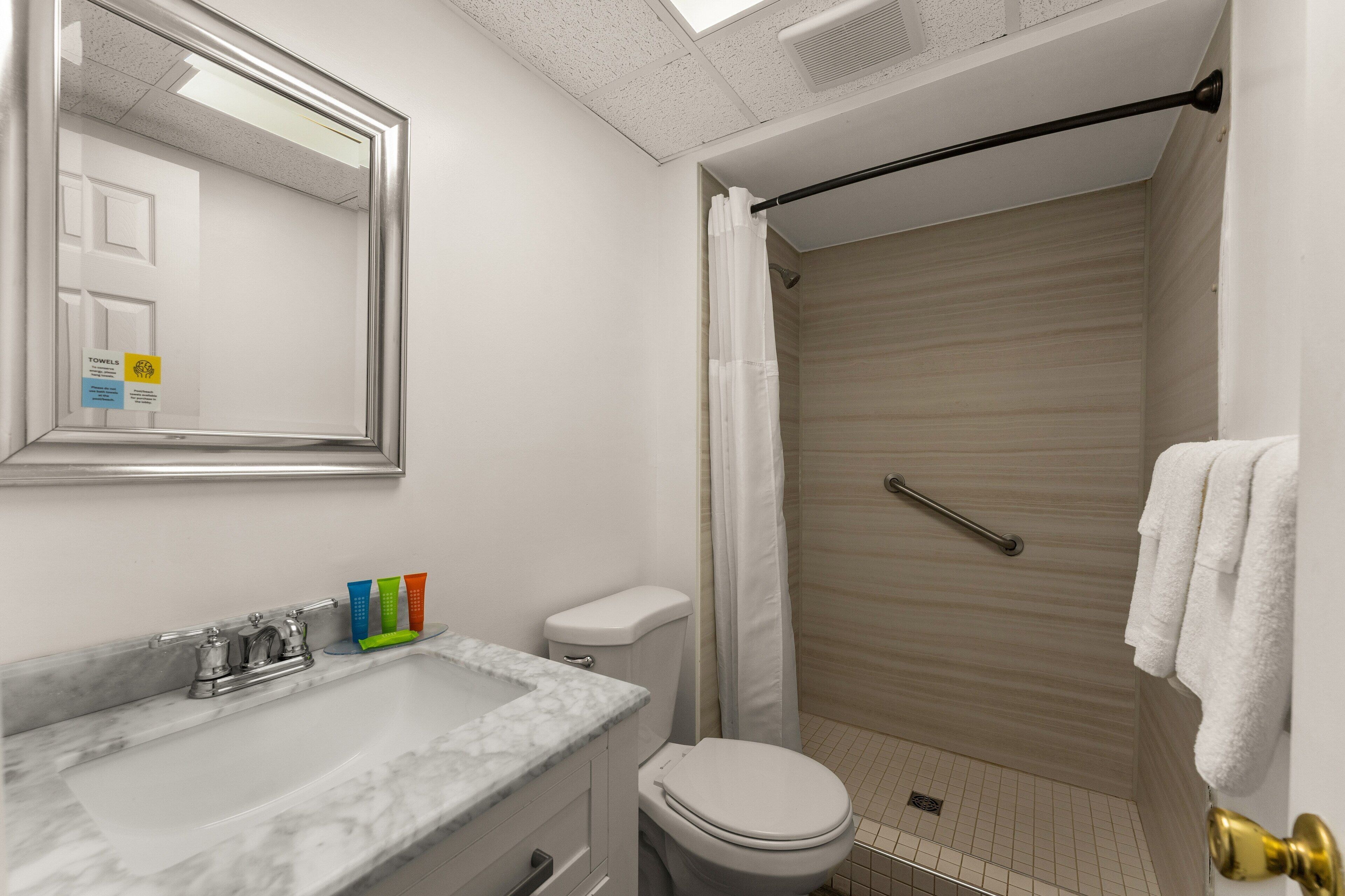 A bathroom with a marble sink, a toilet, a shower with a glass door, and a towel rack.