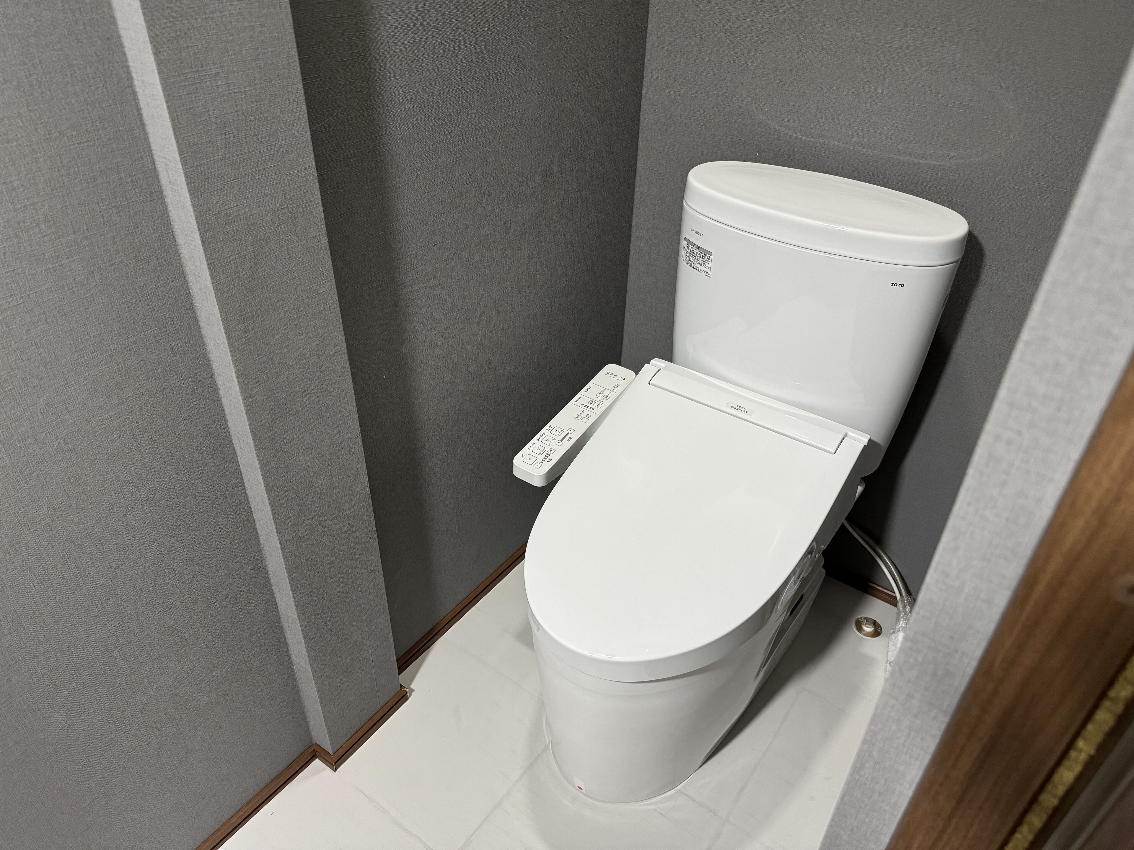 Un inodoro blanco con un panel de control y el logo de la marca Toto.