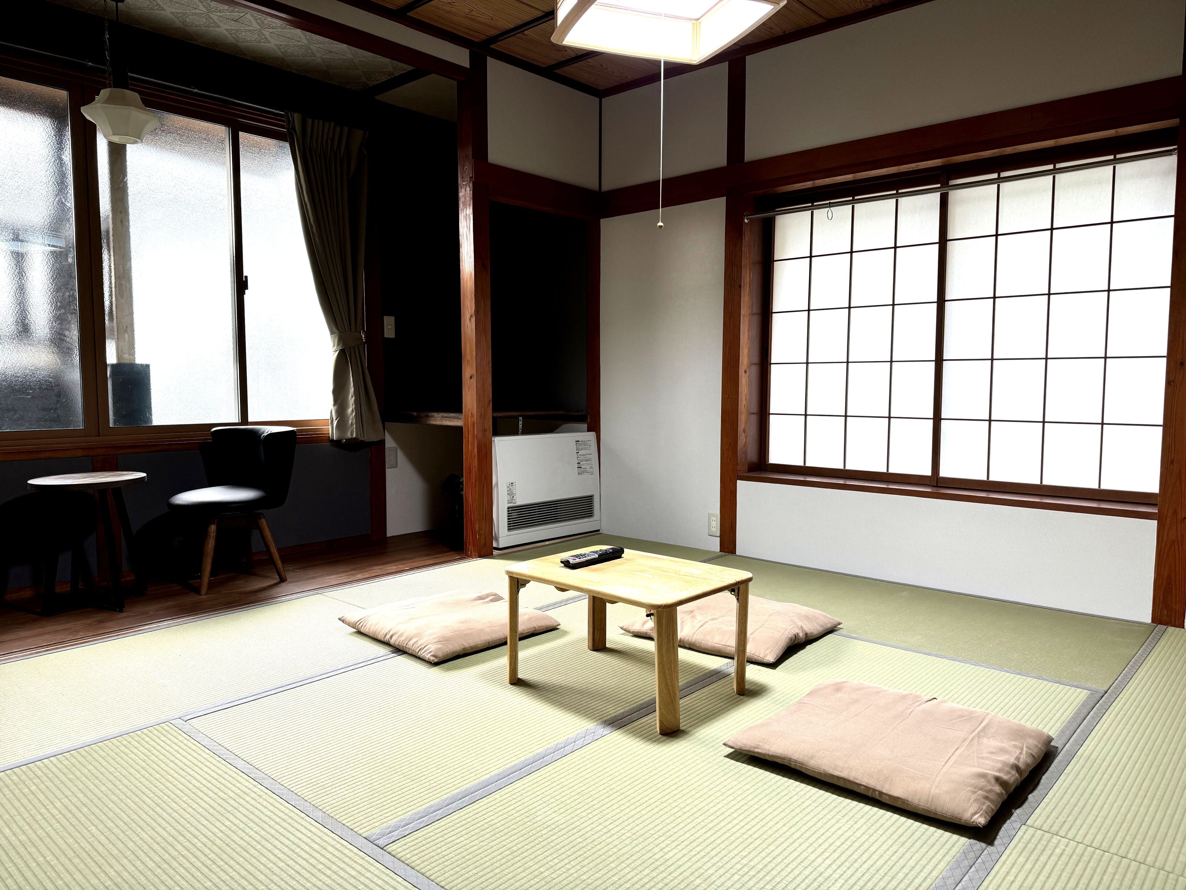A traditional Japanese room with tatami flooring, a low table, cushions, and sliding doors.