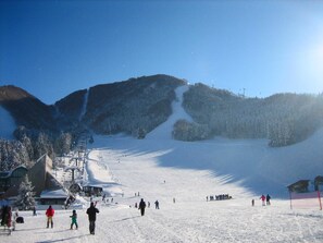 A snowy ski slope with skiers and a lodge in the background. - Wafu Pension MIYAZAWA (Nozawaonsen)