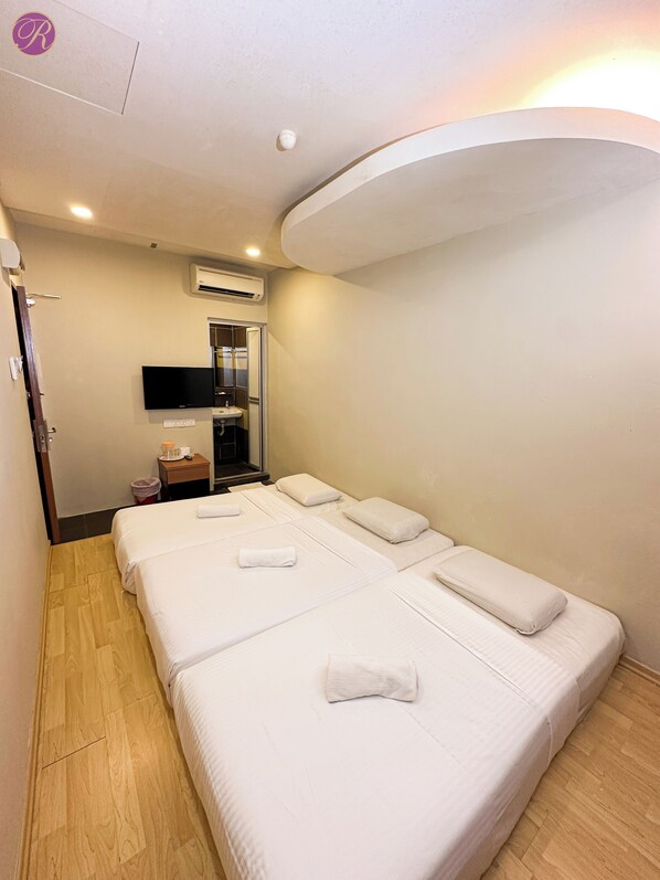 A hotel room with two beds, a TV, a sink, and an air conditioning unit.