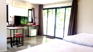 A hotel room with a bed, a desk with a chair, a small refrigerator, and a television. - Wanlapa Farmstay (Lop Buri)