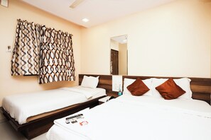 A hotel room with two single beds, a wooden headboard, a large mirror, and a decorative curtain. - Hotel Airport Metro (Mumbai)