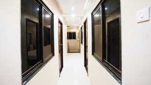 A corridor with doors on both sides, leading to a room with a bed and a bathroom. - Hotel Airport Metro (Mumbai)