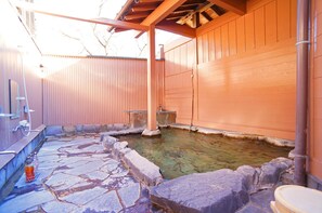 Un onsen japonais traditionnel, avec un sol en pierre et des murs en bois.