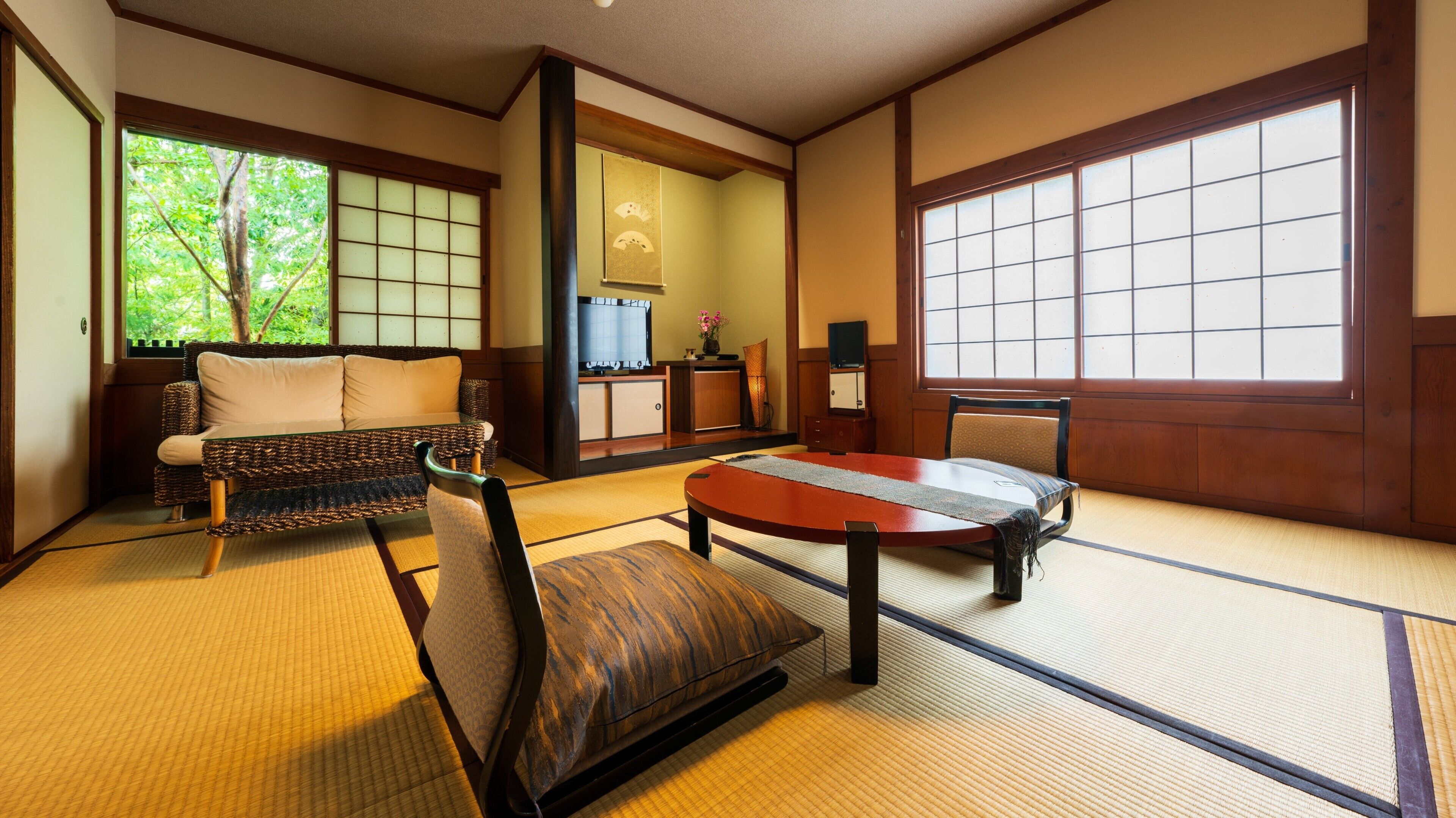 A tatami mat room with a low table, a sofa, and a chair.