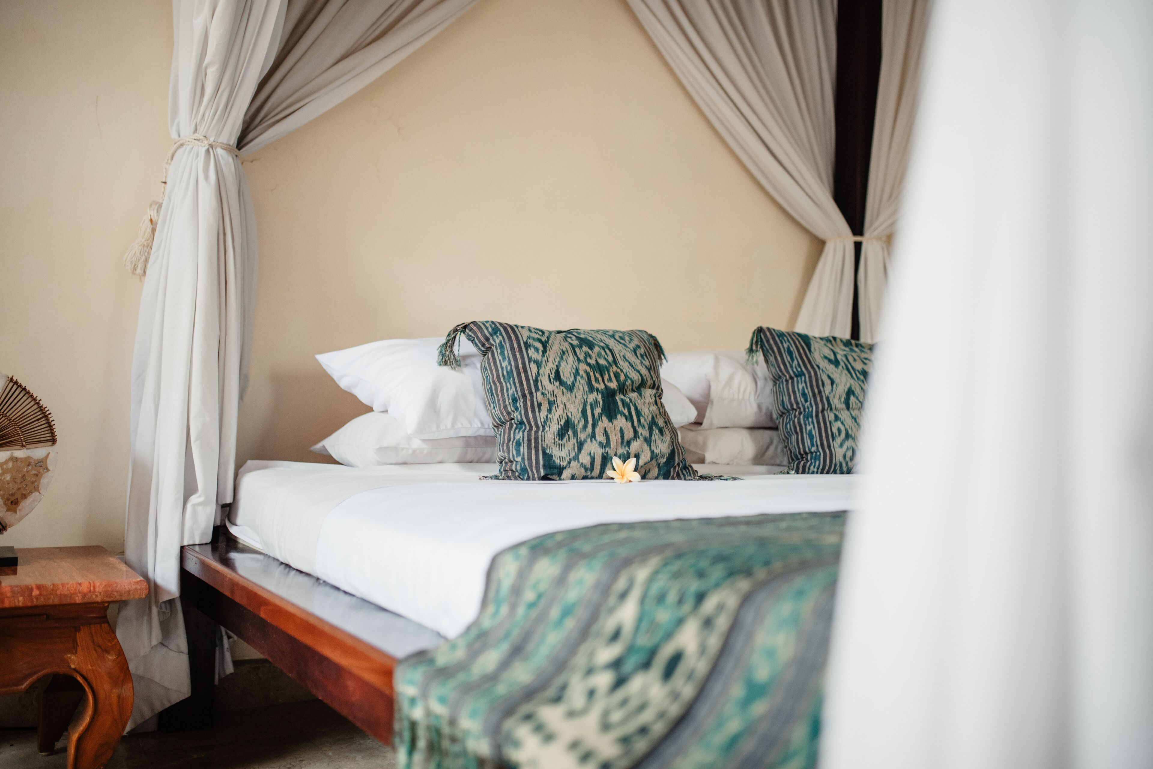 A bed with a patterned blanket, white pillows, and a wooden headboard.