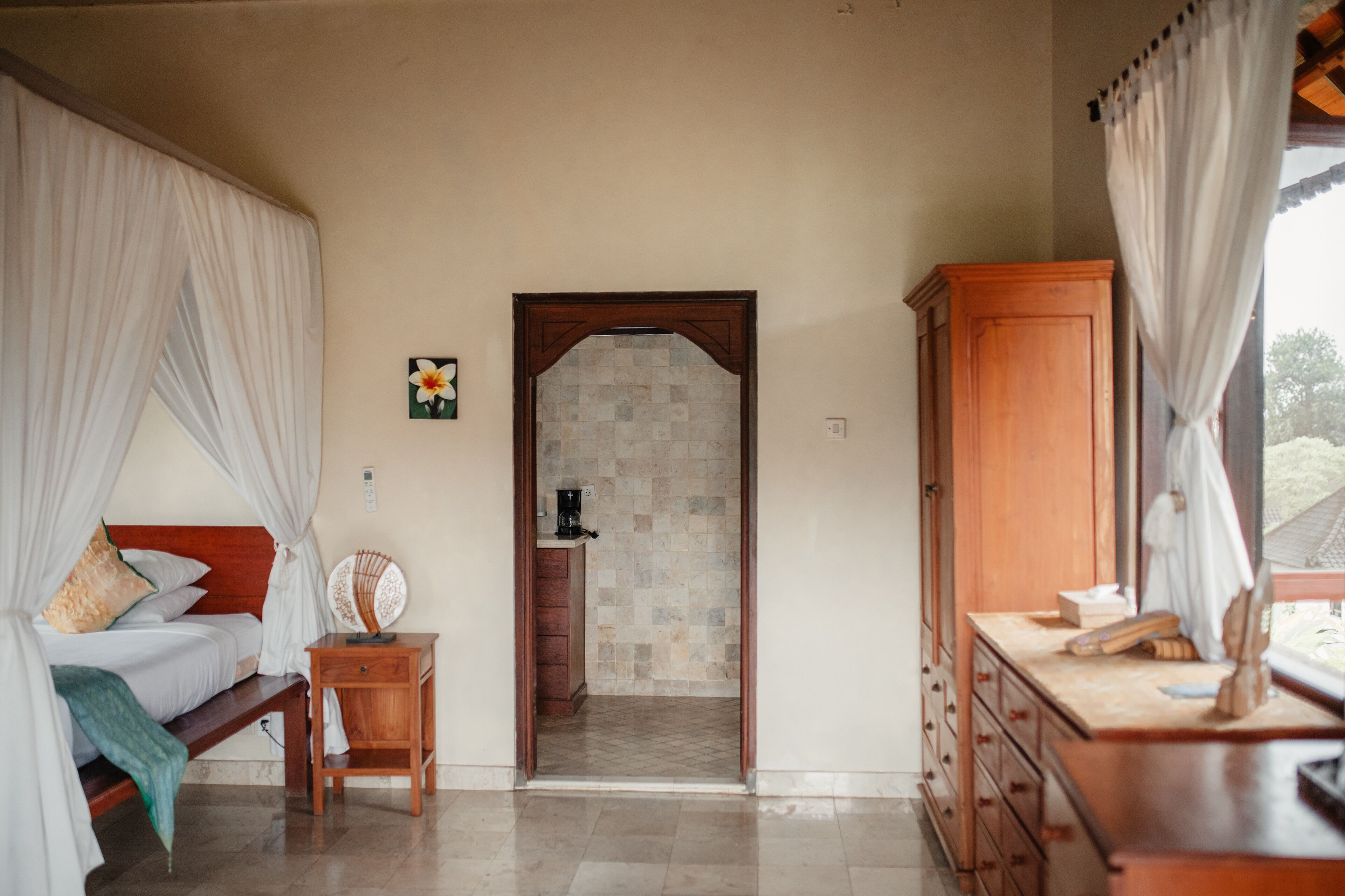 A bedroom with a bed, bedside table, and a view through an arched doorway to a bathroom.