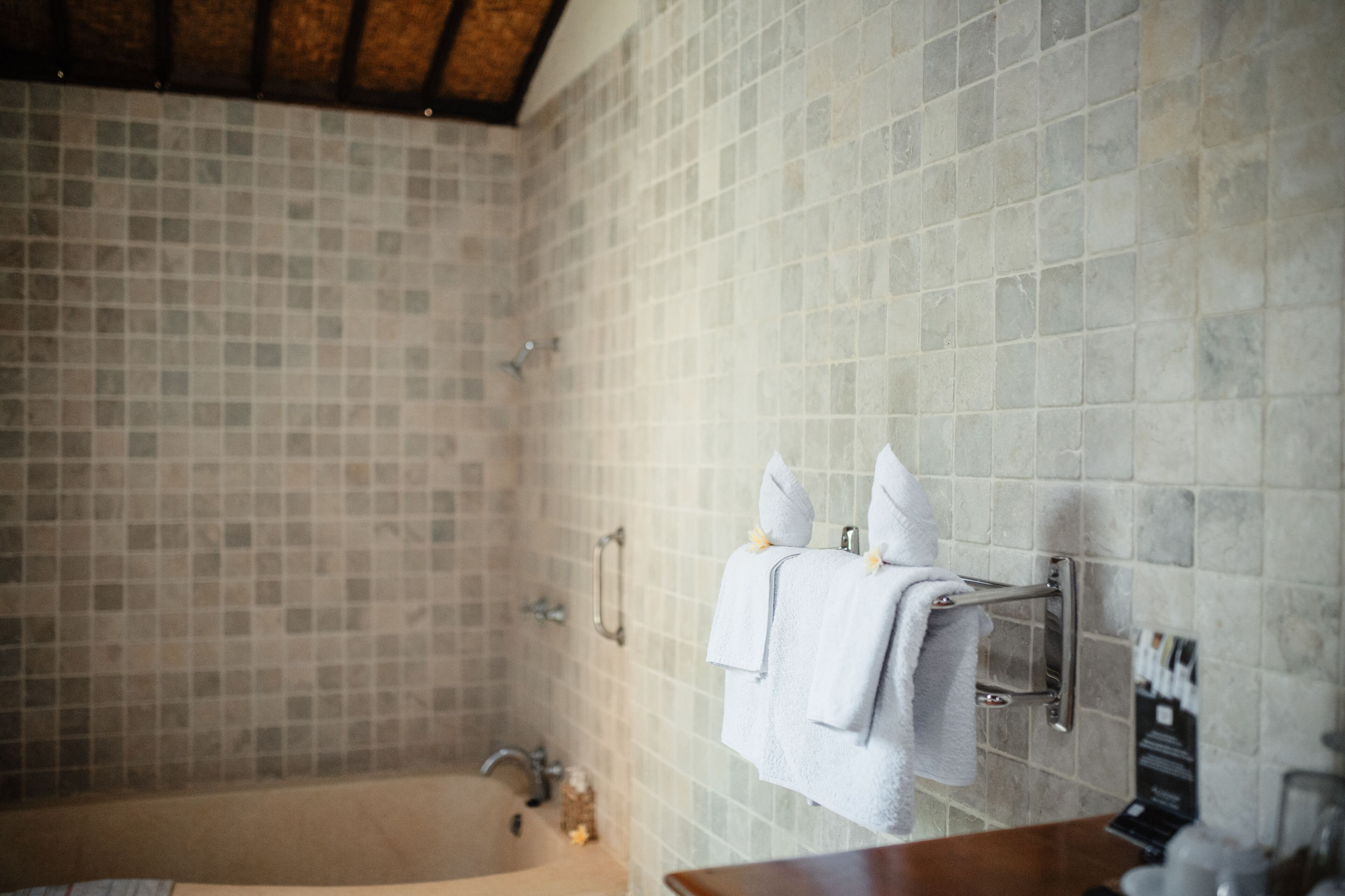 Une salle de bain avec un mur carrelé, une baignoire, un lavabo et un porte-serviettes avec des serviettes.