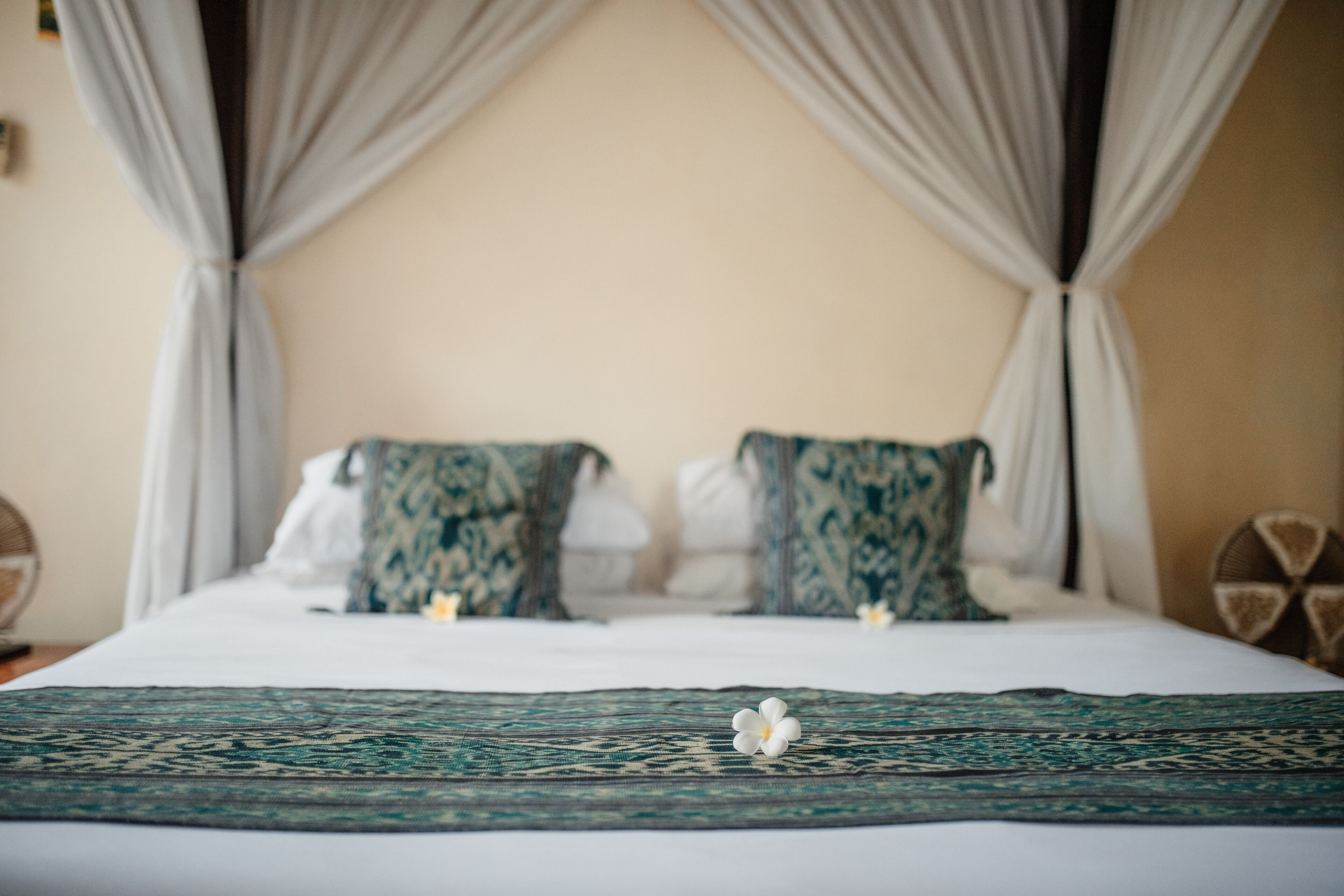 A bed with a green patterned bedspread and two pillows with a green and white pattern.