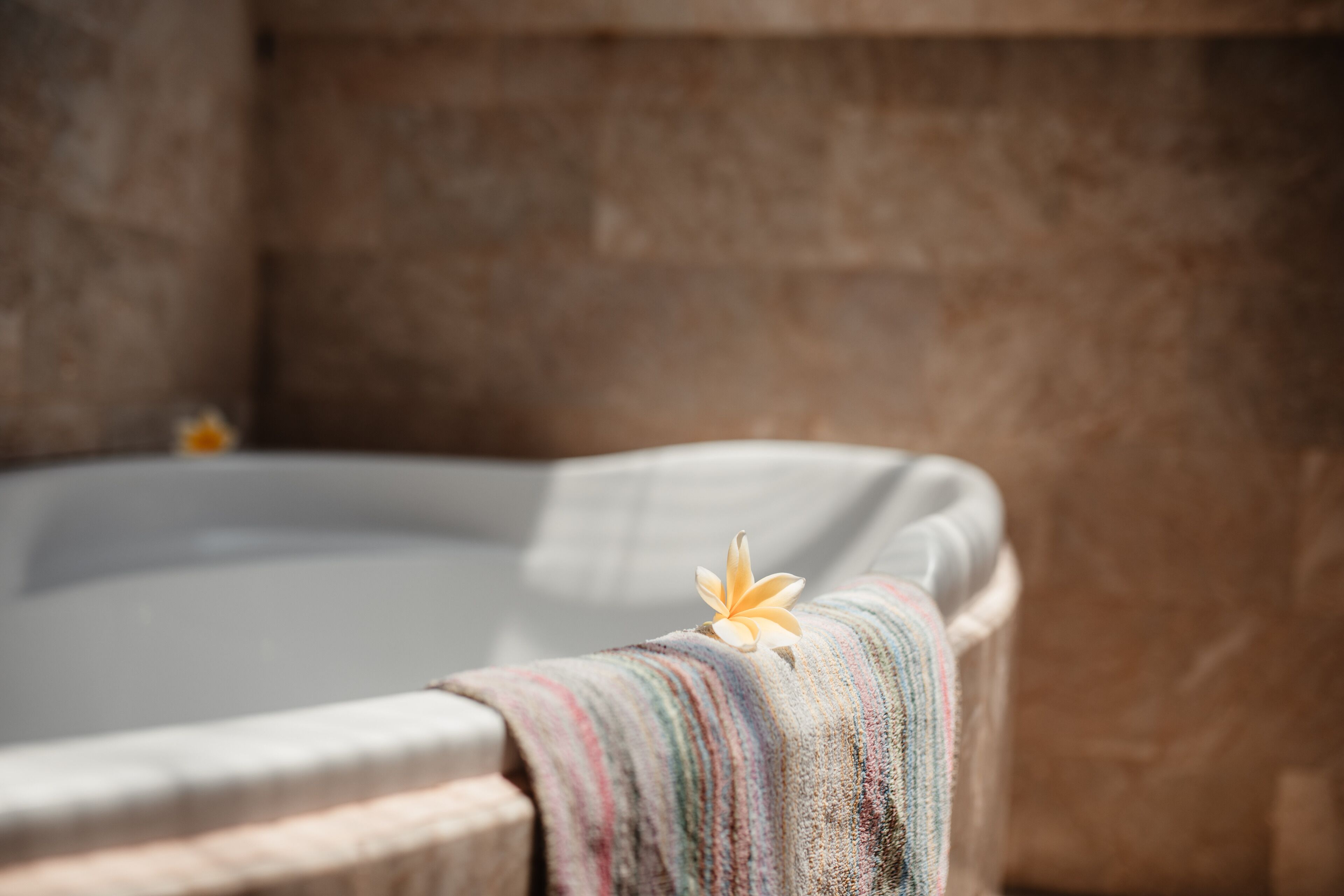 A hot tub with a flower on the edge, surrounded by a stone wall.