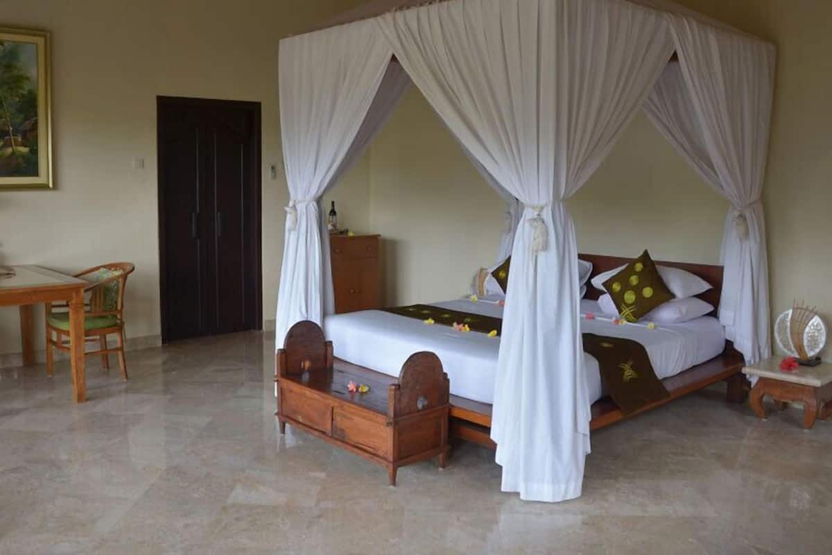 A four-poster canopy bed with a wooden headboard, a small bedside table, and a chair.