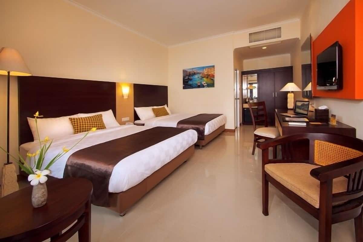 Habitación de hotel con dos camas, un escritorio, una silla, un televisor y un cuadro en la pared.