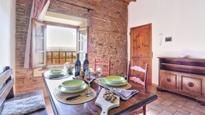Un comedor con pared de ladrillo rústico, vigas de madera y vistas al campo.