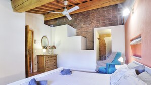 Un dormitorio con cama, cómoda, espejo, silla y escalera.