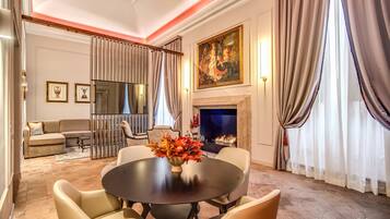 A formal dining room with a round table, chairs, a vase of flowers, a fireplace, and a painting on the wall.