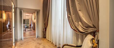 Un pasillo con una silla, cortinas y piso de baldosas.