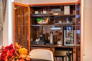 Ein Holzkabinent mit Regalen, gefüllt mit Tassen, einer Kaffeemaschine und einem gerahmten Bild.