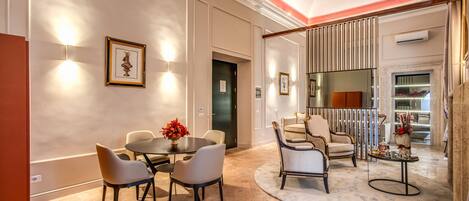 A spacious dining area with a round table and chairs, a small side table with decorative items, and a large mirror reflecting the room.