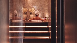 A modern bathroom with marble walls, a large mirror, and a vanity with a towel rack.