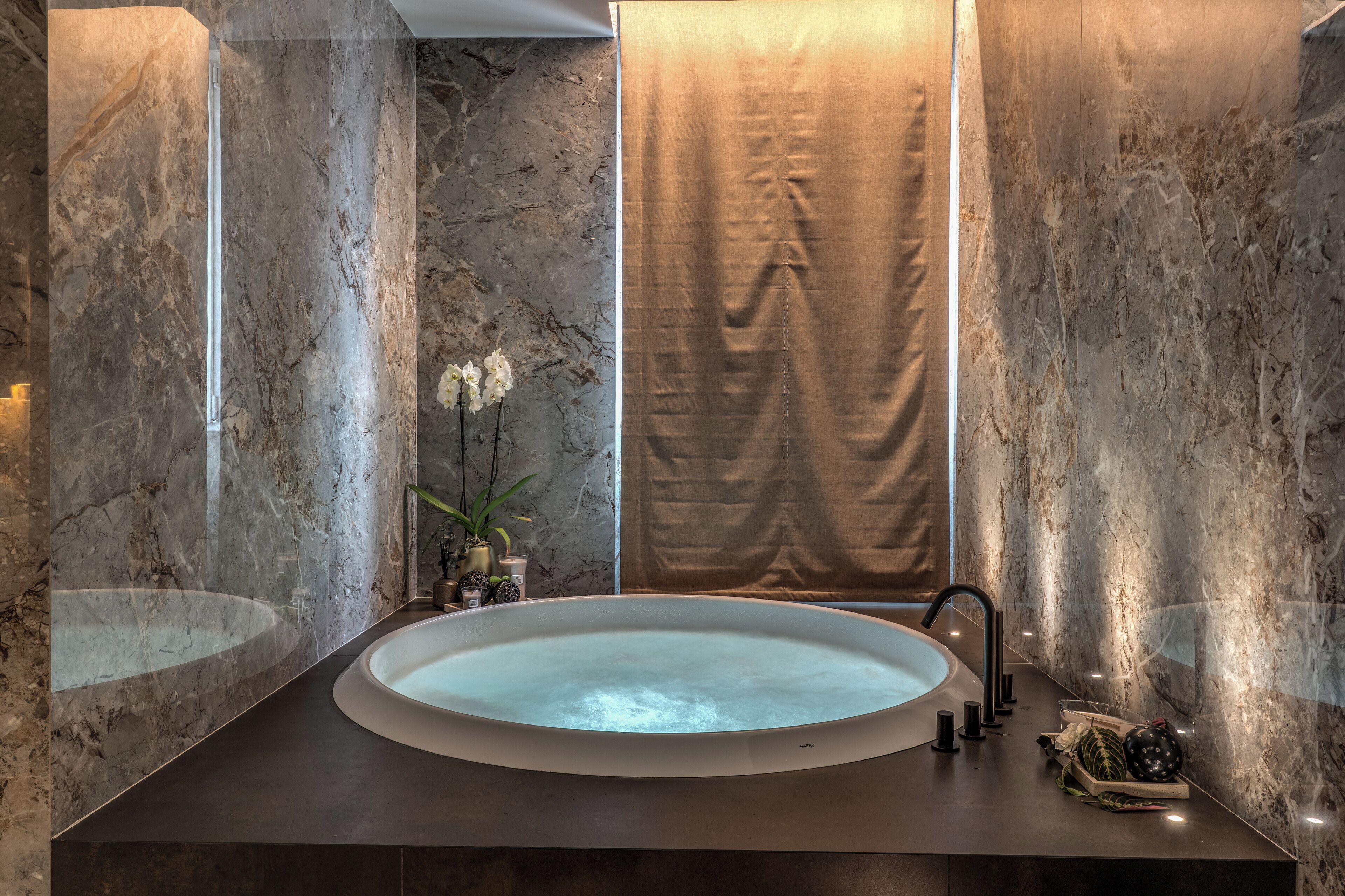 Ein modernes Badezimmer mit Waschbecken aus Marmor, einer großen Badewanne und einem Vorhang.