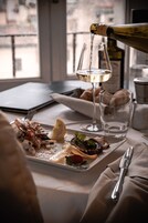 A dining table with a plate of food, a bottle of wine, and glasses.