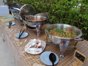 A buffet setup with various dishes and utensils. - The Camping Field (Suan Phueng)