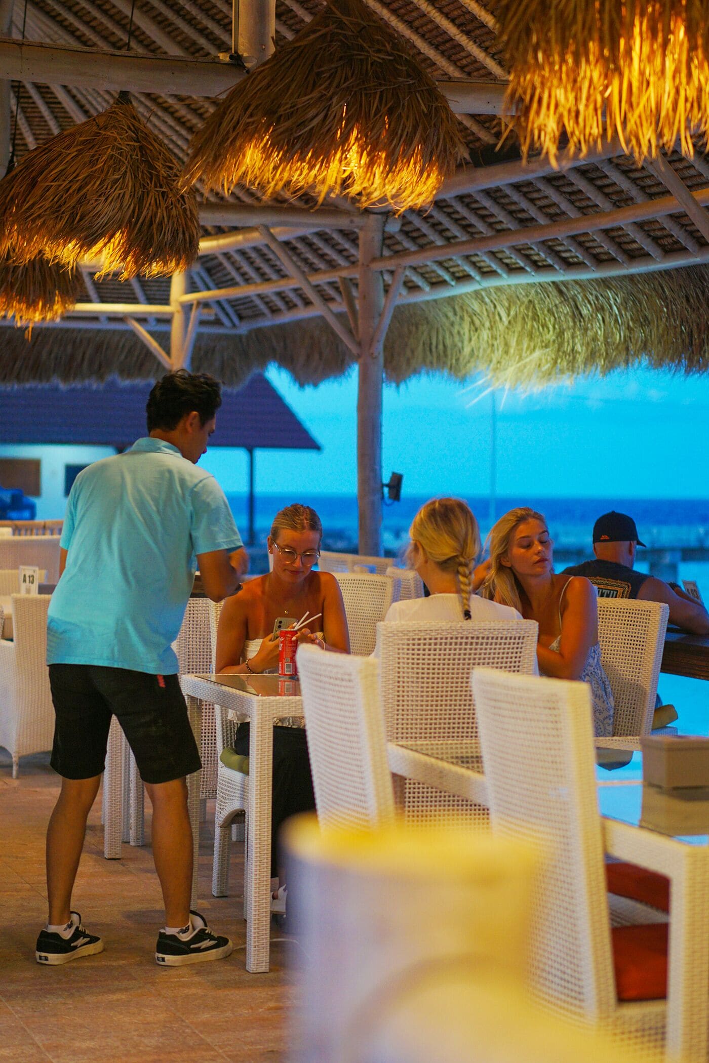 A beachside restaurant with outdoor seating and a view of the ocean.
