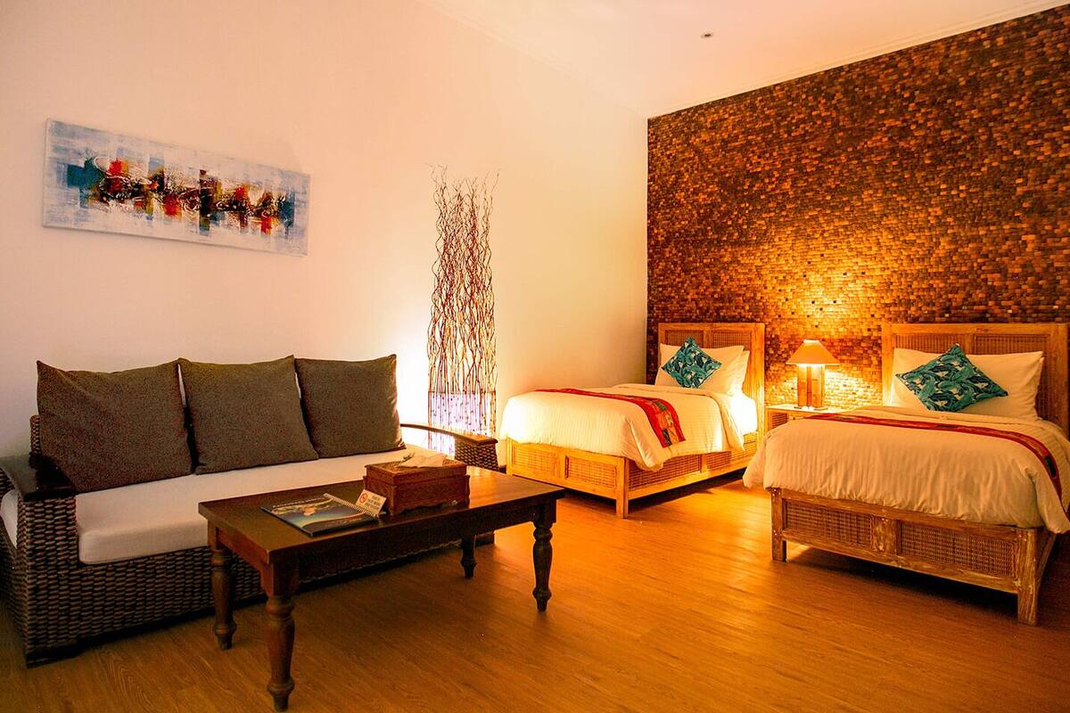 Ein Zimmer mit einer Couch, zwei Betten, einem Couchtisch und einer Wand mit Mosaikmuster.