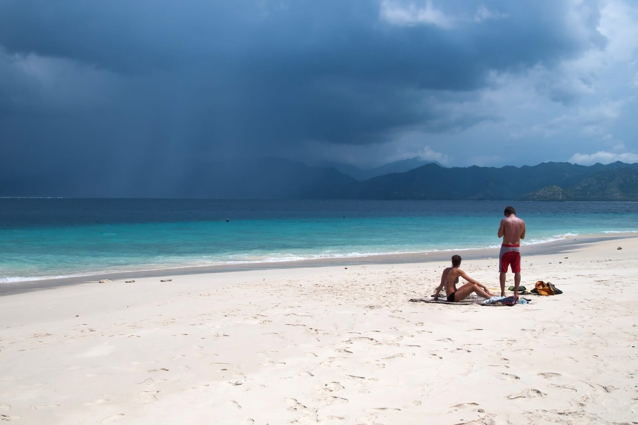 Ein Strand mit blauem Himmel und Bergen im Hintergrund.
