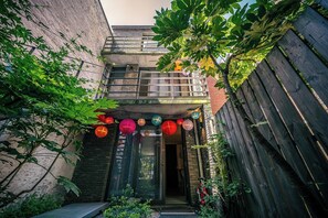 A courtyard with a wooden fence, a brick wall, and a building entrance with colorful lanterns. - Antwerp For Two Bed & Breakfast (Antwerp)