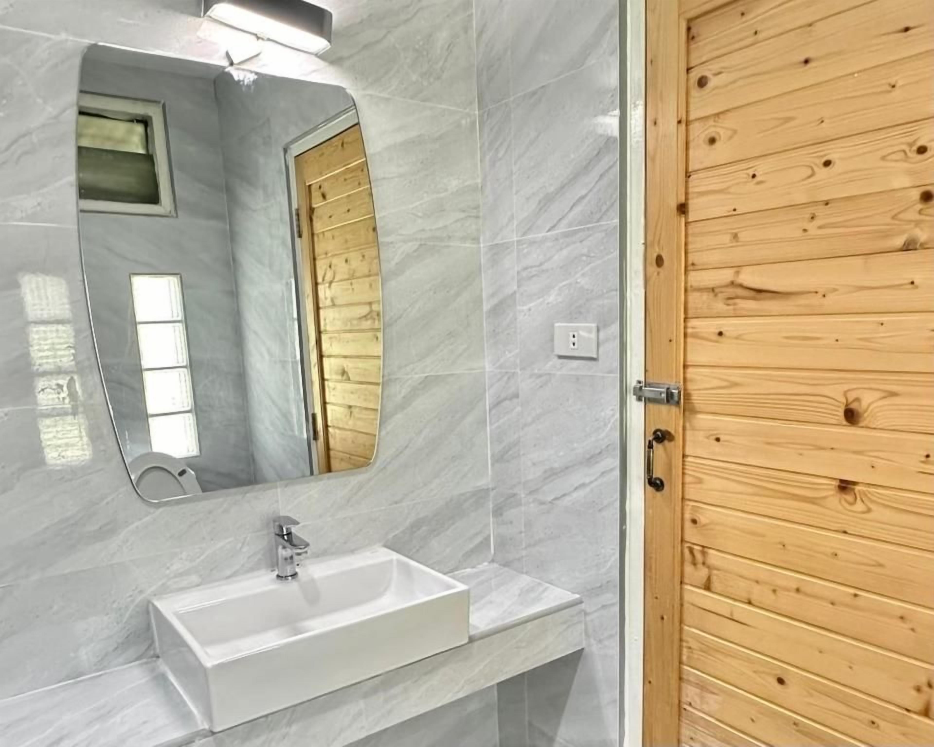 A bathroom with a white sink, a mirror, and a wooden door.