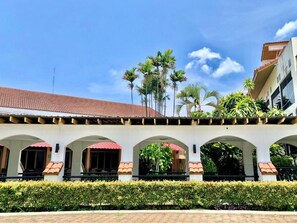A building with a tiled roof, arched walkways, and a row of palm trees. - DadD Resort by Lopburi Inn Resort (Lop Buri)