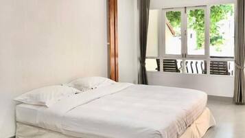 A single bed in a room with a large window and curtains.