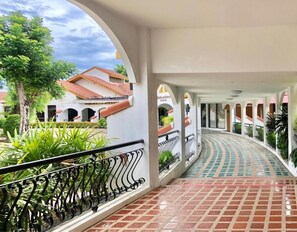 A covered walkway with a tiled floor, white walls, and black railings. - DadD Resort by Lopburi Inn Resort (Lop Buri)