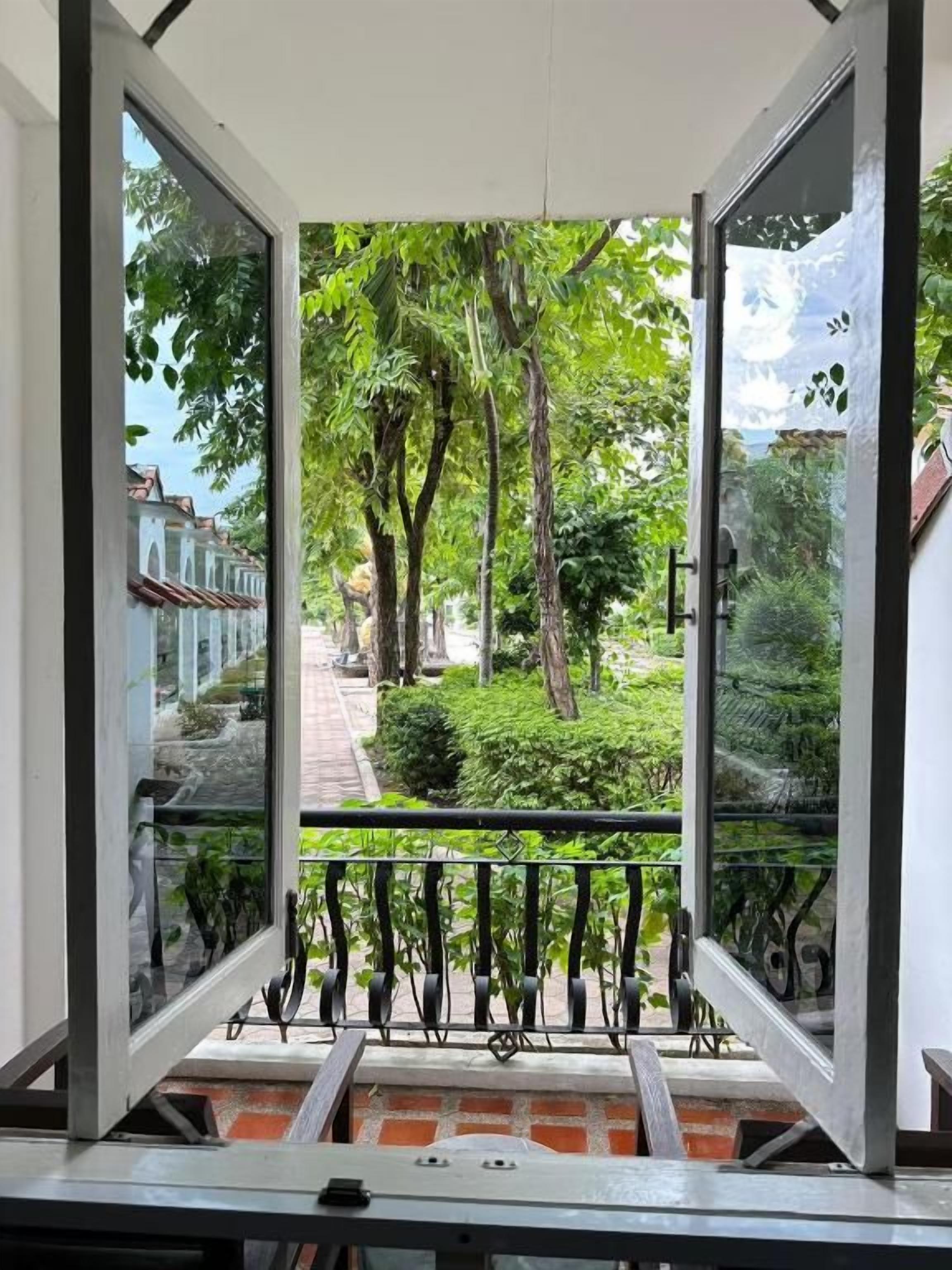 Vista de uma varanda com grade de metal, com vista para um caminho e vegetação.