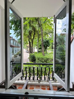A view from a balcony with a metal railing, overlooking a pathway and greenery. - DadD Resort by Lopburi Inn Resort (Lop Buri)