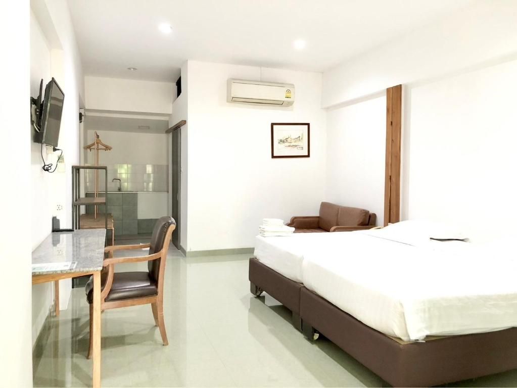 Camera d'albergo con un letto, una scrivania e una sedia. Presenta una TV a muro e un condizionatore d'aria.