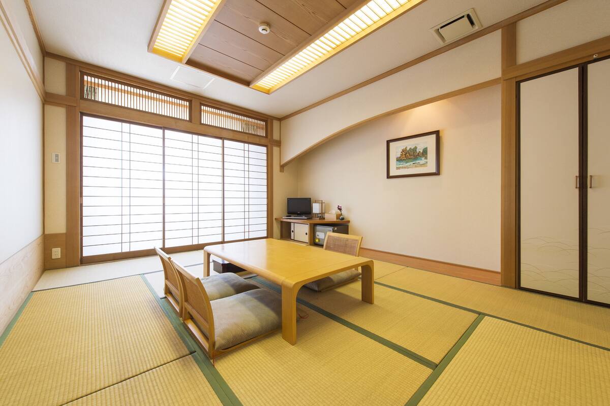 A traditional Japanese room with tatami flooring, a low table, cushions, and sliding doors.