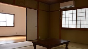 Una habitación japonesa tradicional con suelo de tatami, una mesa de madera baja, puertas correderas y una ventana con paneles shoji.