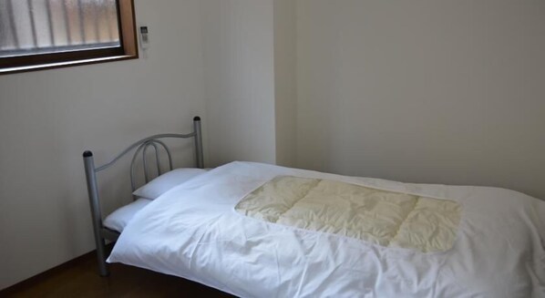 A single bed with a metal frame, white bedding, and a quilt. - Tatamiya Inn (Kyoto)