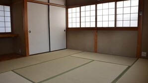 Una habitación japonesa tradicional con suelo de tatami, puertas correderas y un ventanal grande con vidrios de cuadrícula.