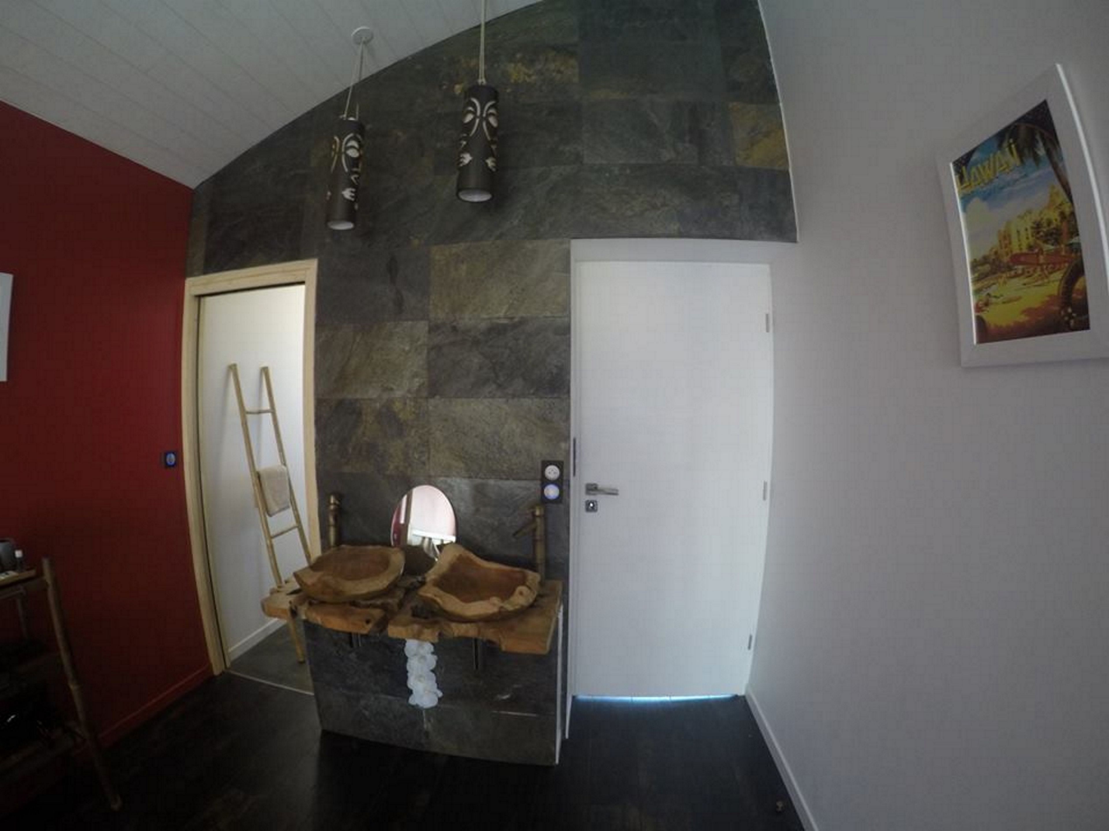 Ein Zimmer mit einer Steinsäule, einer Holzleiter, einer weißen Tür und einem gerahmten Bild an der Wand.