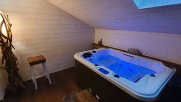 A hot tub with a control panel and a wooden bench.