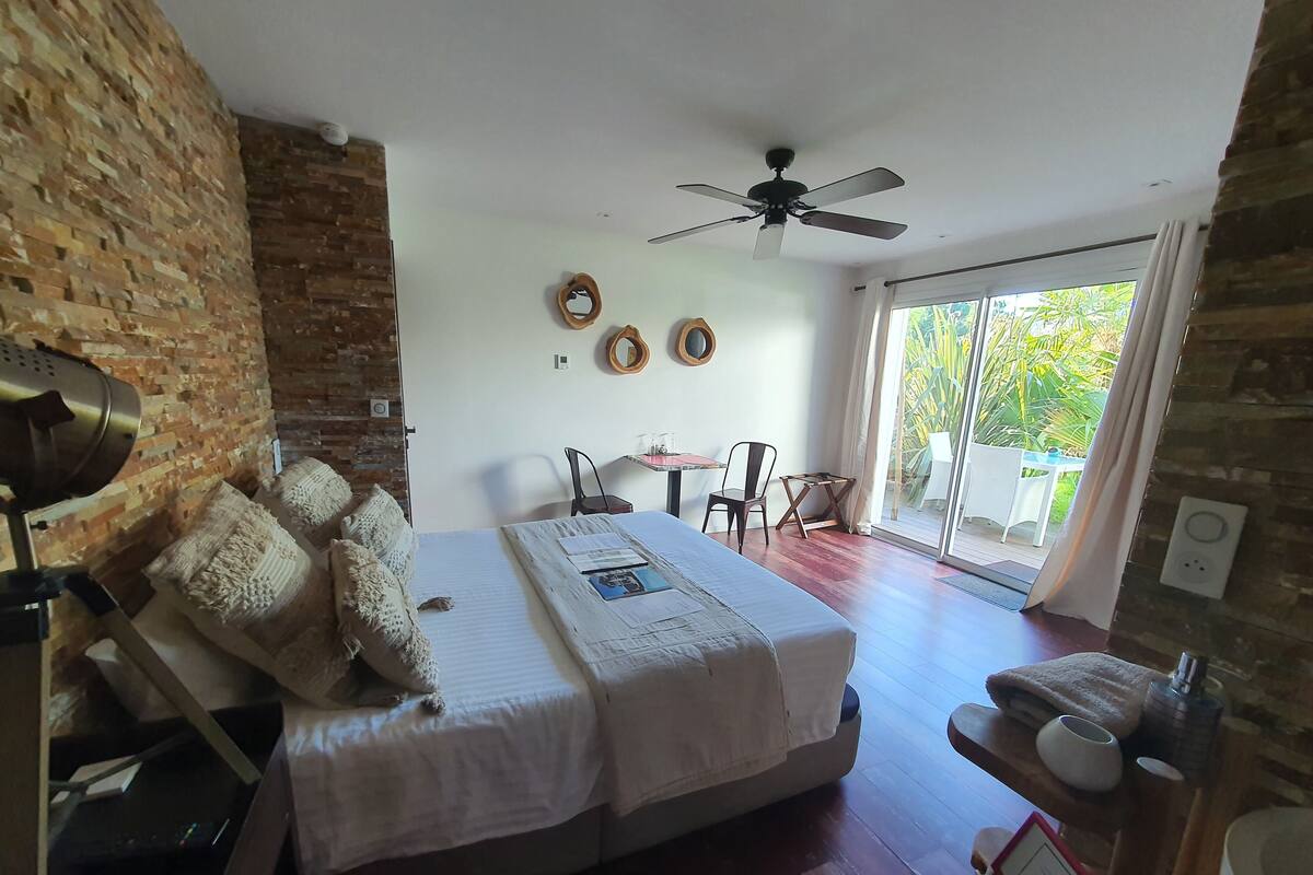 A bedroom with a bed, a desk, a chair, and a ceiling fan.