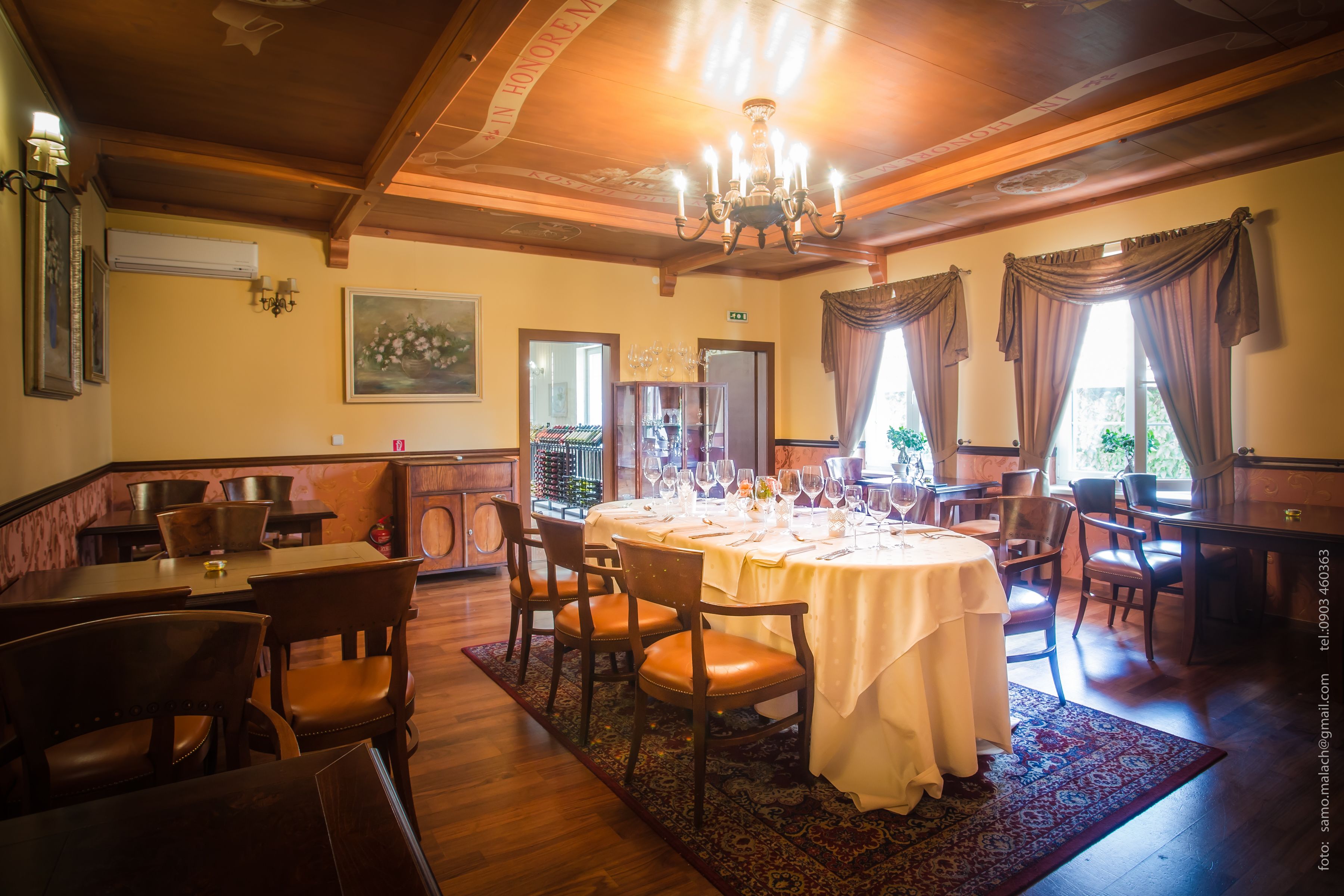 A restaurant with wooden furniture, white tablecloths, and a chandelier.